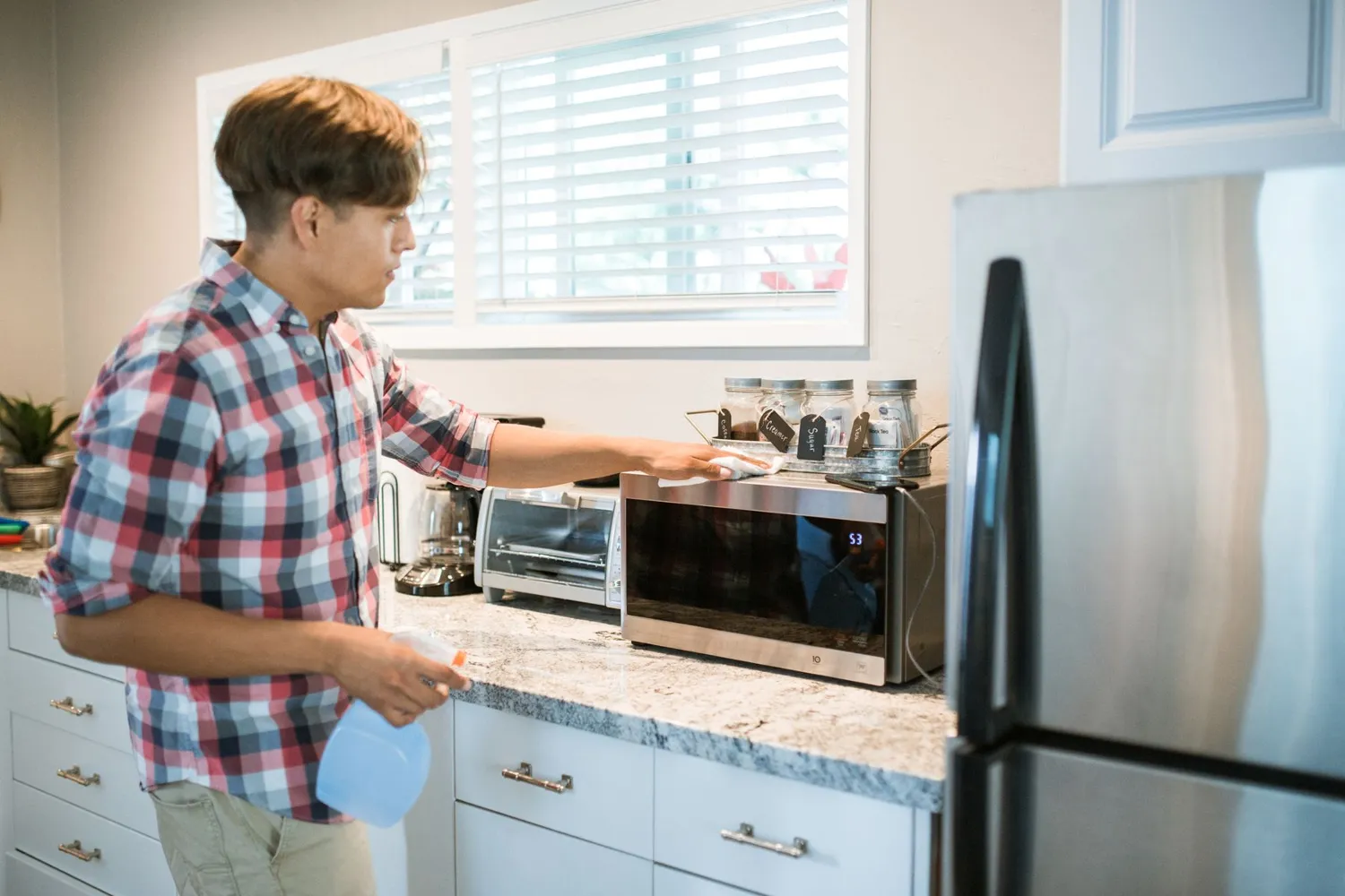 A gloved hand wiping a kitchen counter with a cloth
